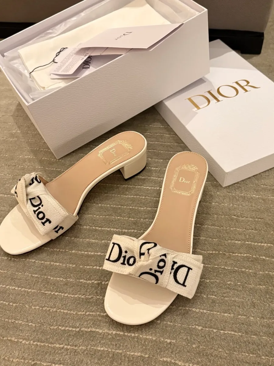 Пара белых шлёпанцев с вышитым бантом Dior и открытая коробка, ракурс сверху