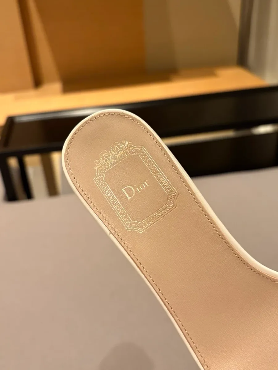 Крупный план бежево-белой стельки шлёпанца с тиснёным логотипом Dior в рамке