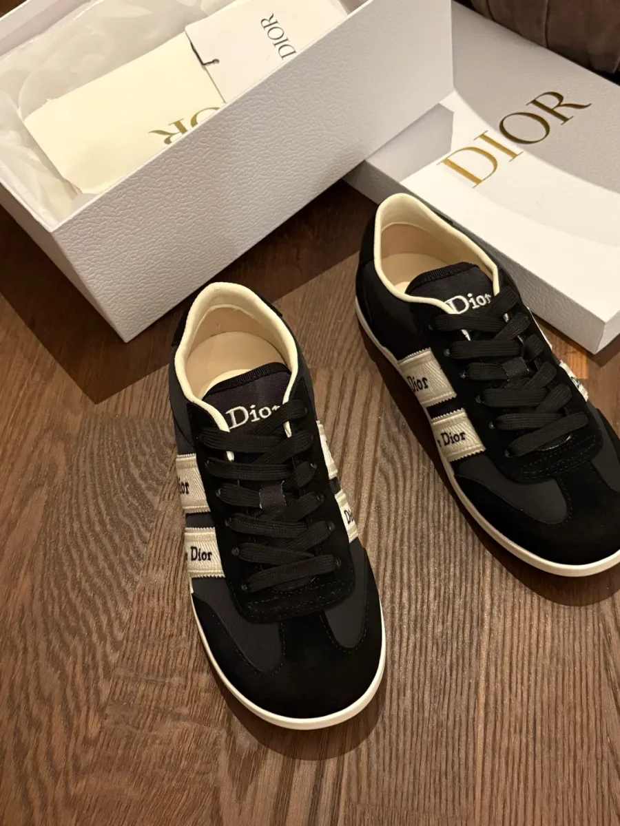 Чёрные кеды Dior Ribbon рядом с коробкой, вид сверху на деревянном полу