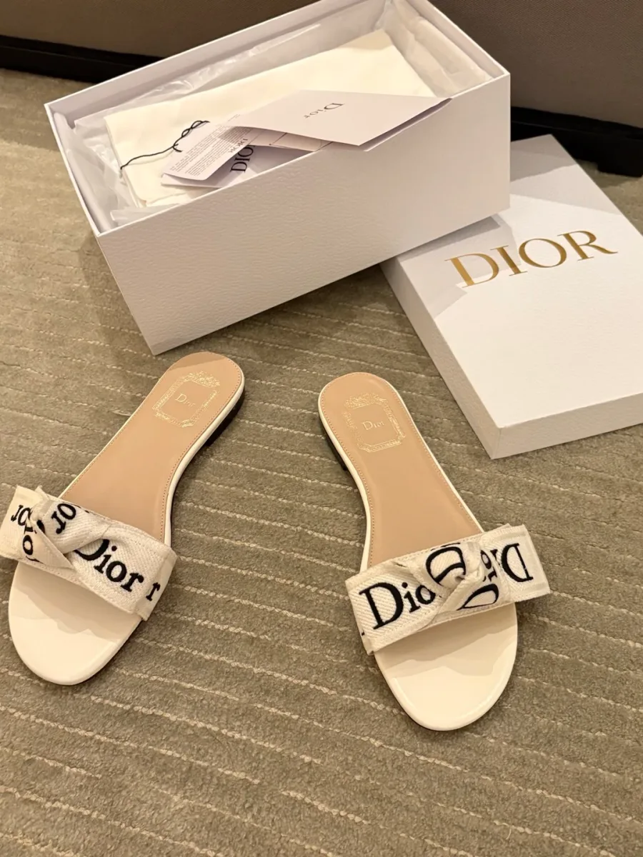Белые шлёпанцы Dior с бантом на перемычке рядом с фирменной коробкой