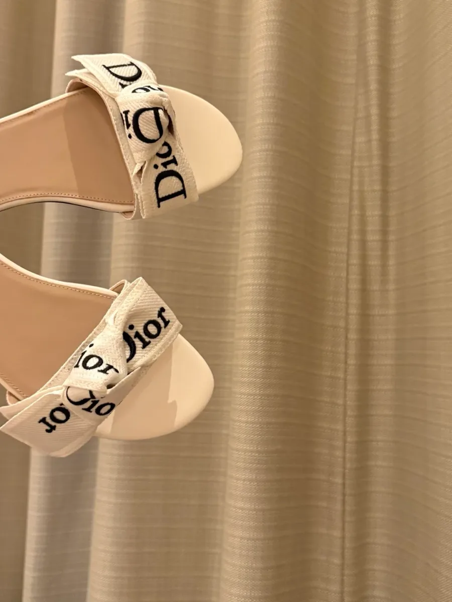 Крупный план текстильных перемычек шлёпанцев Dior с вышивкой и бантом