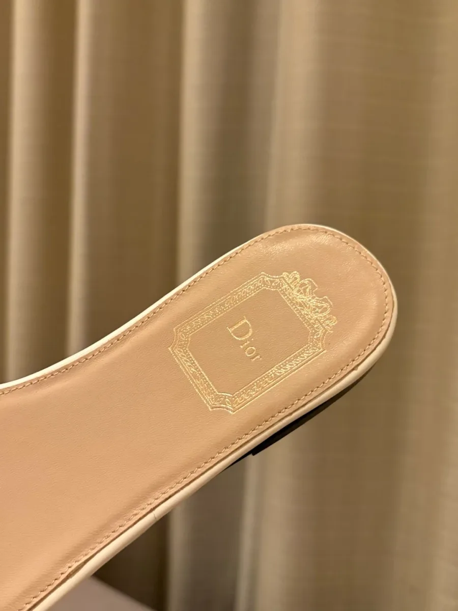 Крупный план бежевой кожаной стельки шлёпанцев Dior с золотистым логотипом