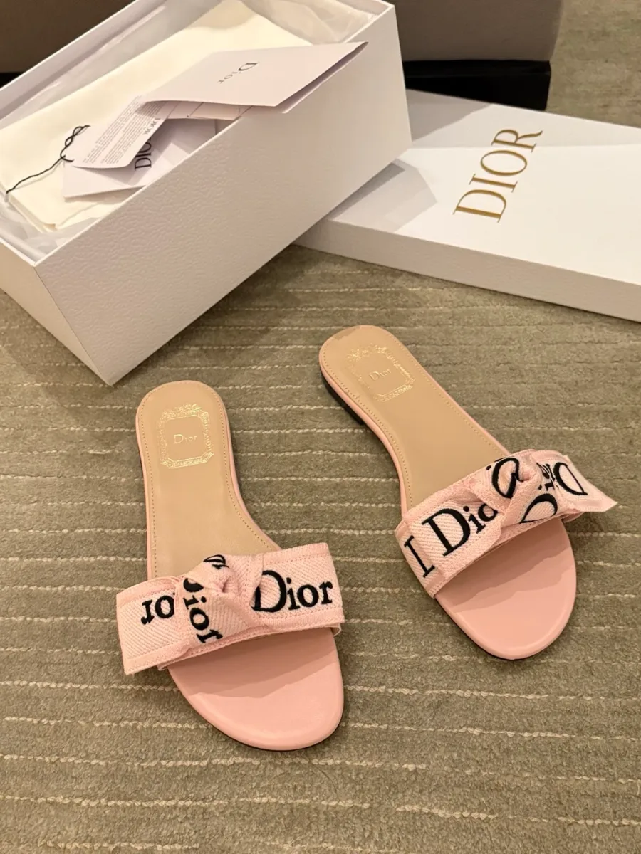 Розовые шлёпанцы Dior с вышитым бантом рядом с фирменной коробкой