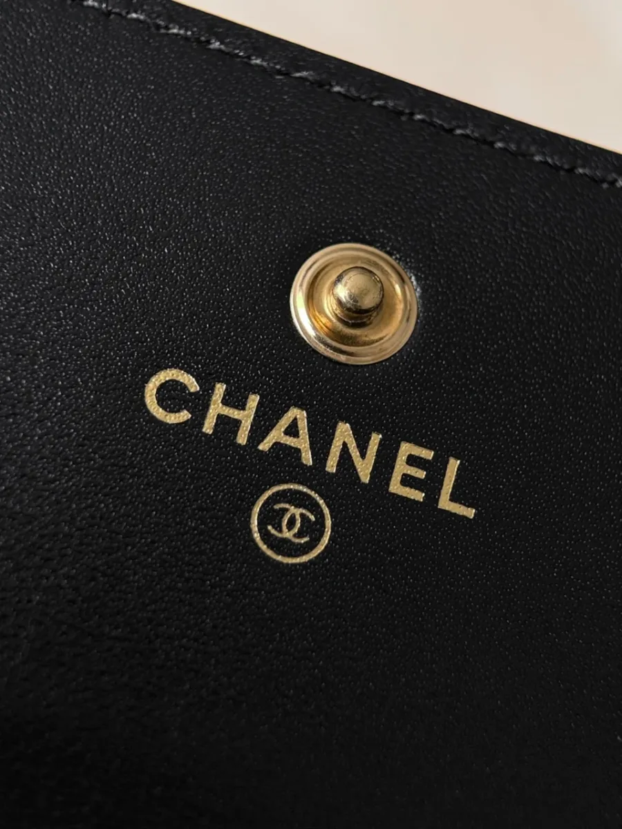 Крупный план золотистой кнопки и логотипа Chanel внутри кошелька