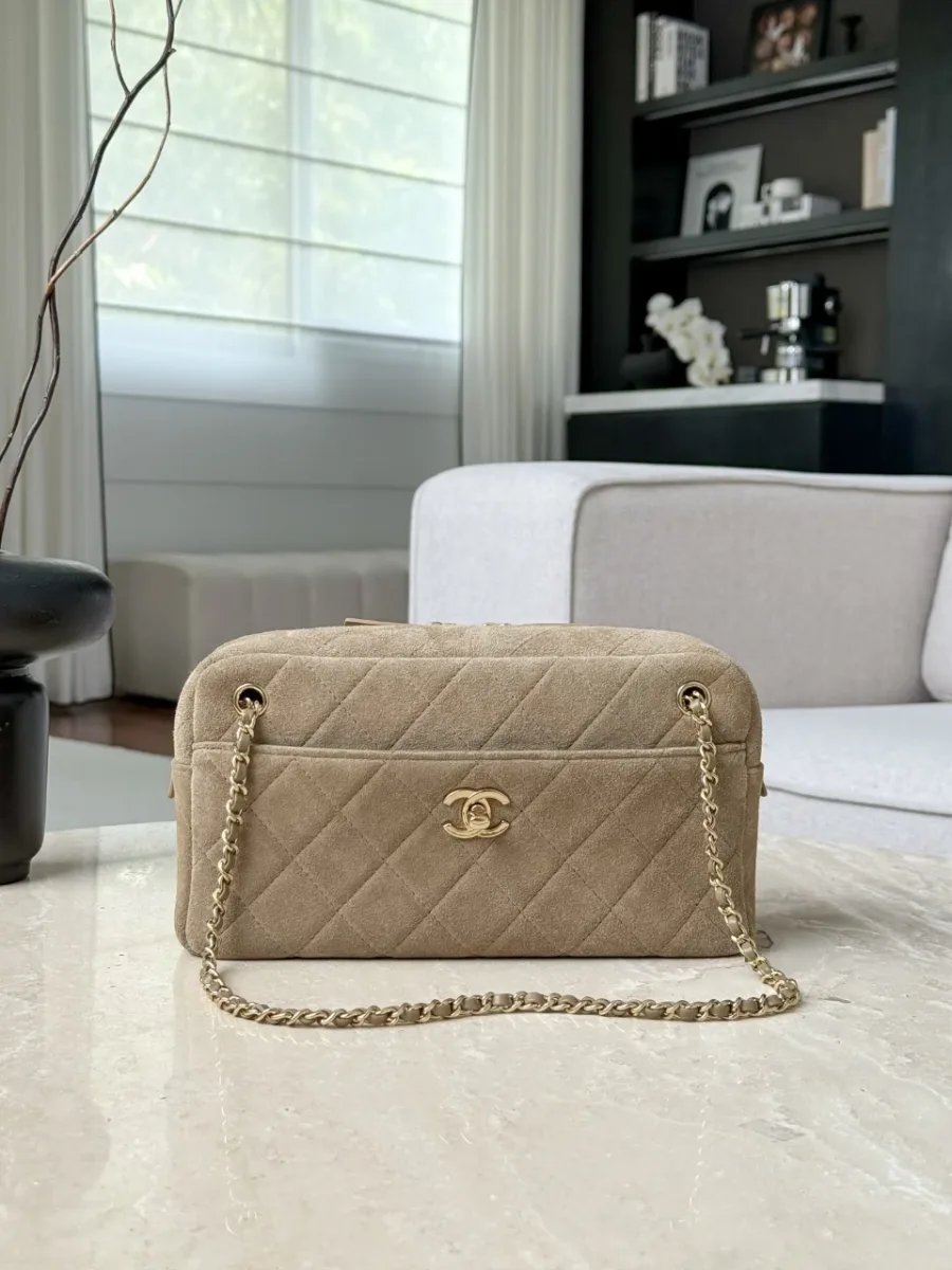 Фронтальный вид бежевой сумки Chanel Camera Bag на светлом столе