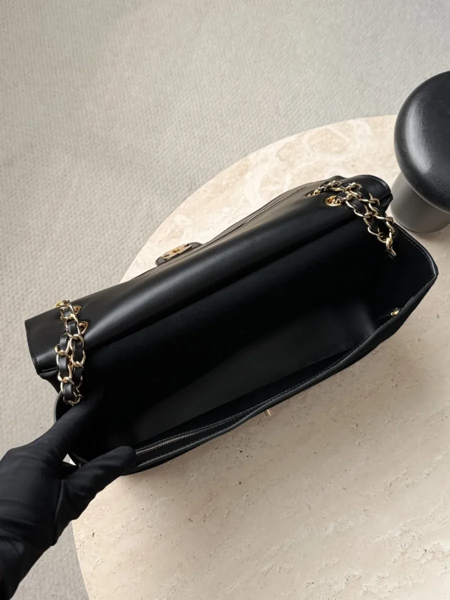 Вид сверху на открытую сумку Chanel с черной кожаной подкладкой