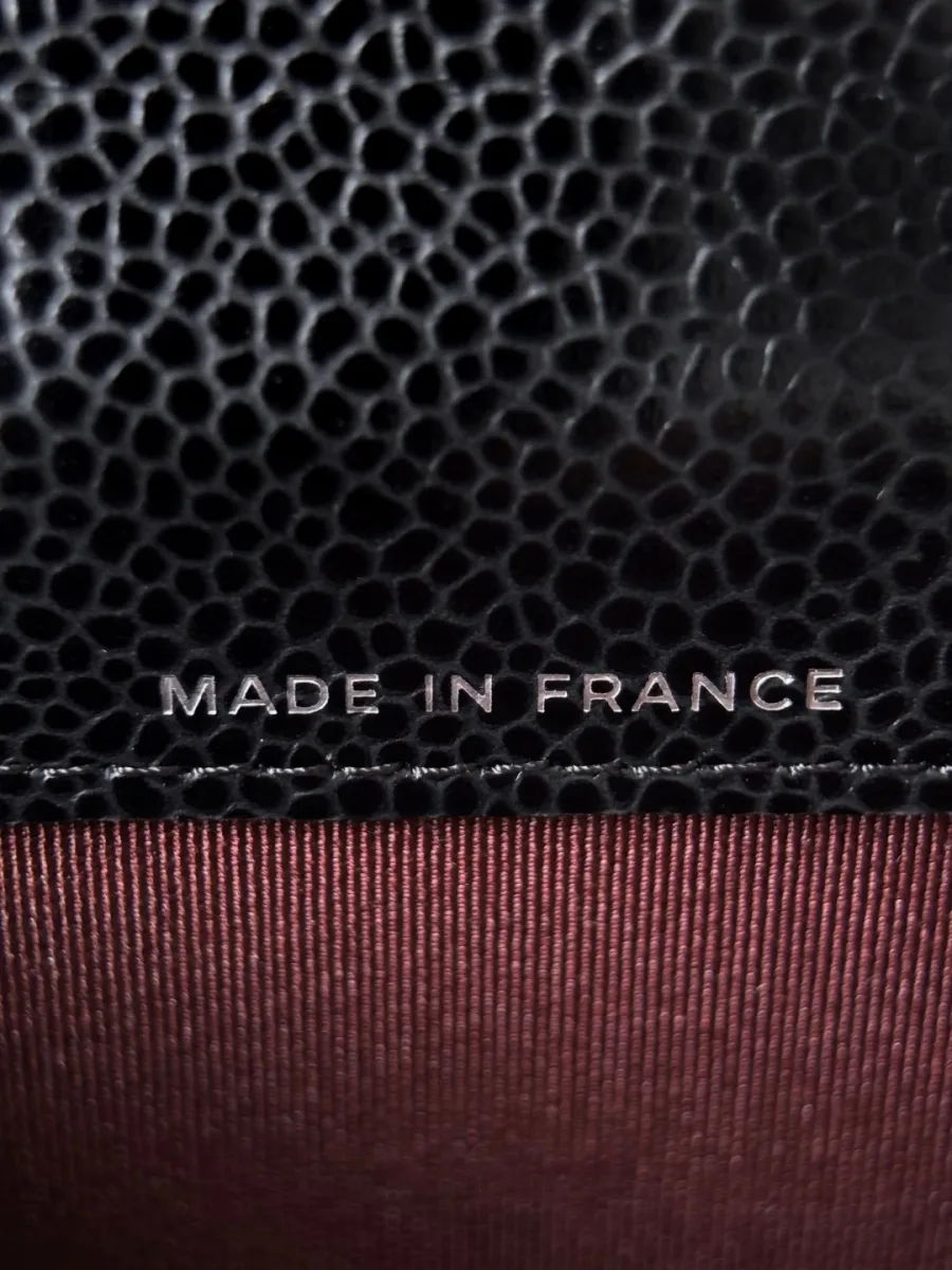 Крупный план серебристого тиснения Made in France на бордовой подкладке