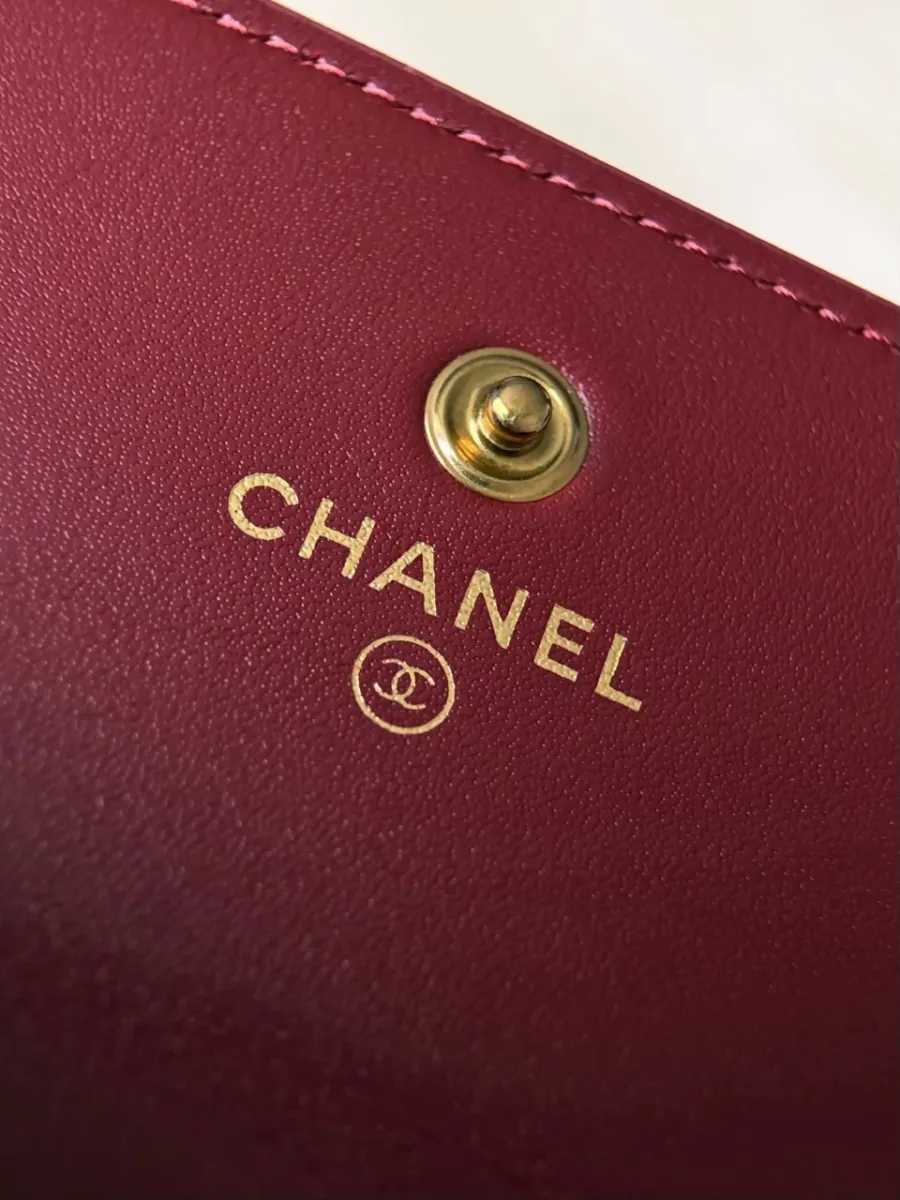 Крупный план золотистого логотипа Chanel и кнопки внутри кошелька.