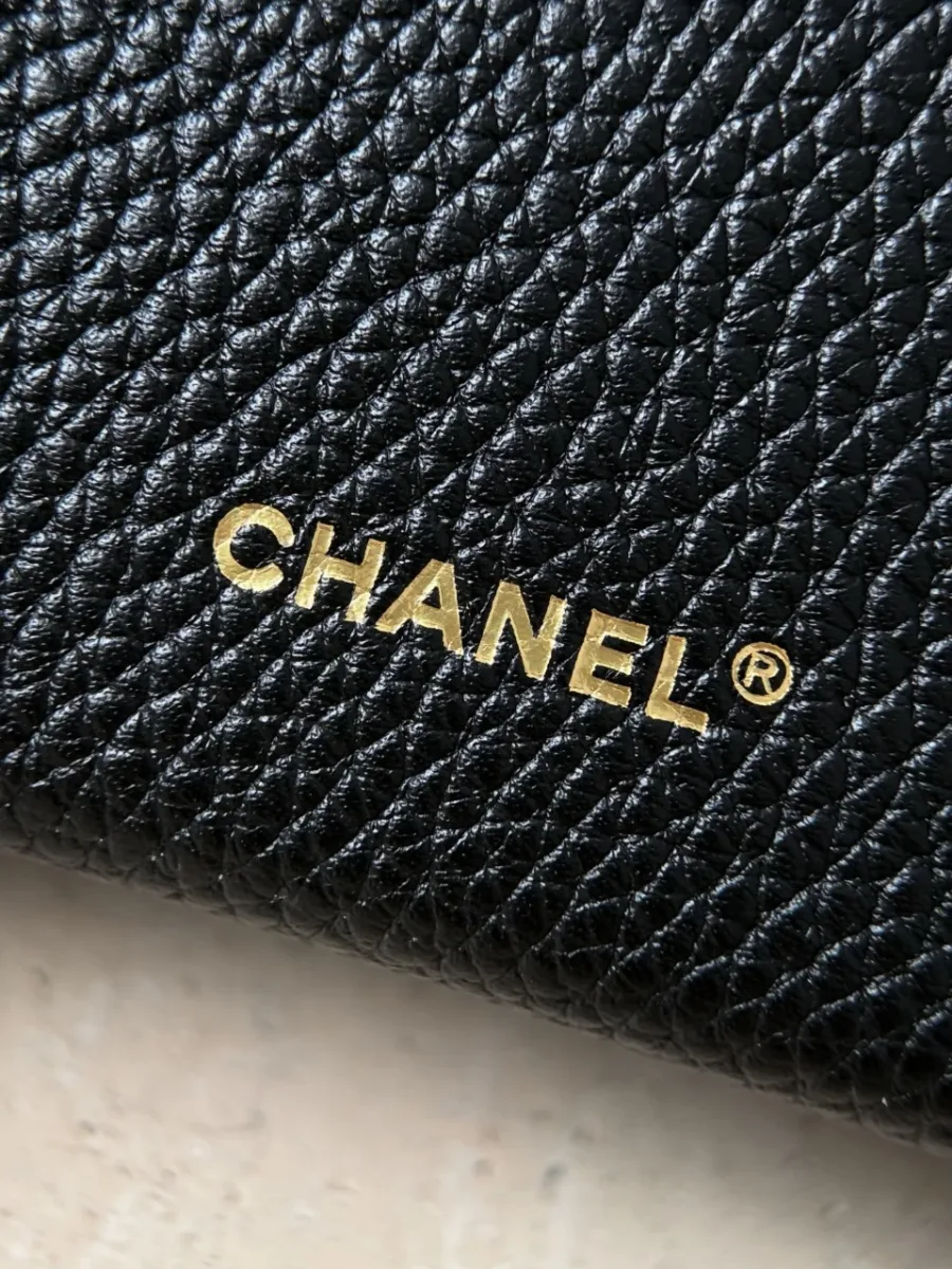 Крупный план золотистого тиснения Chanel на задней стороне сумки