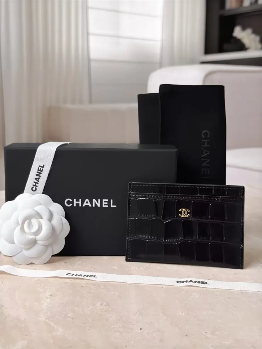 Чёрный картхолдер Chanel рядом с фирменной коробкой и белой камелией