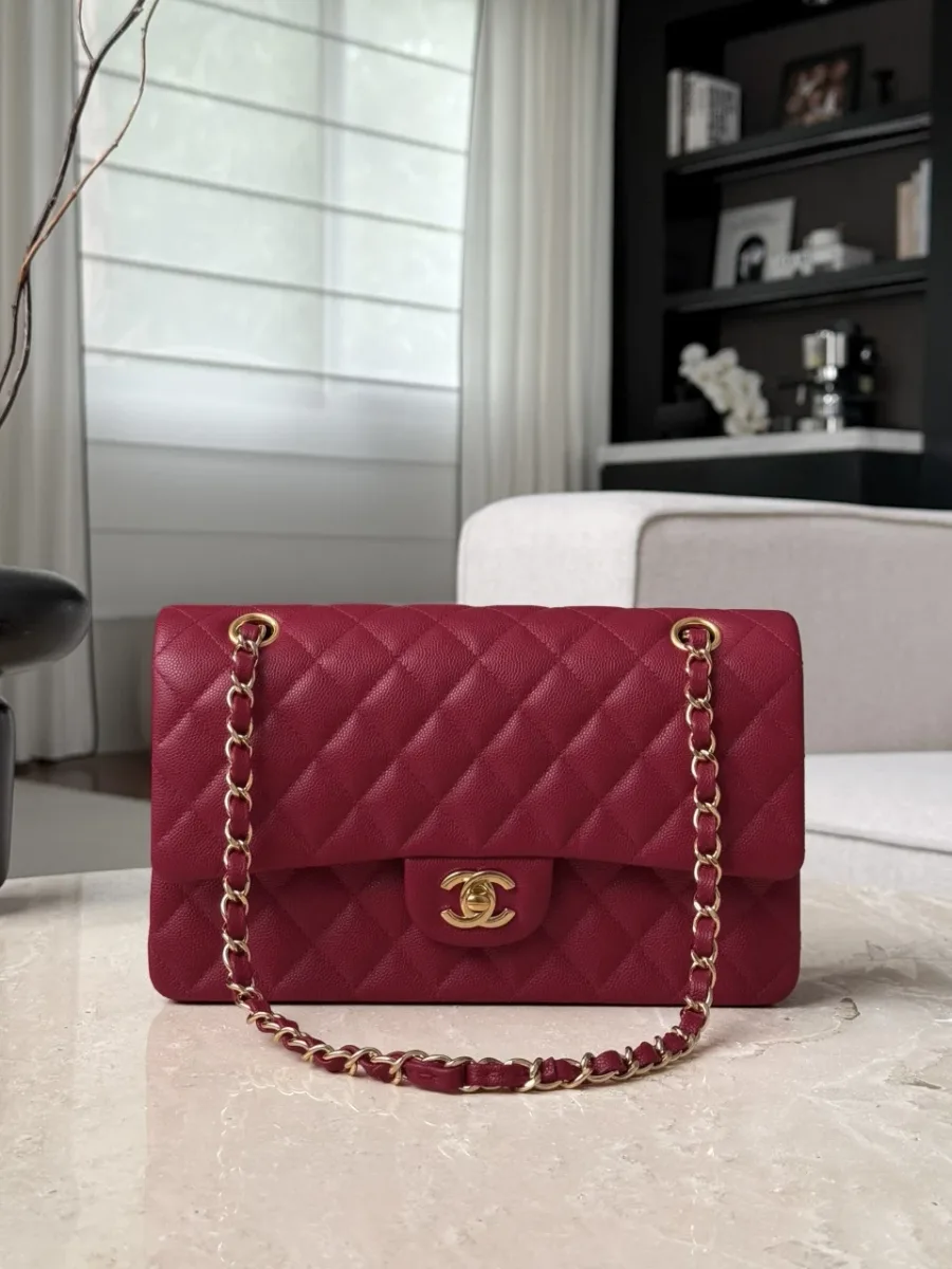Бордовая сумка Chanel Classic Flap 25 на светлом столе, фронтальный ракурс