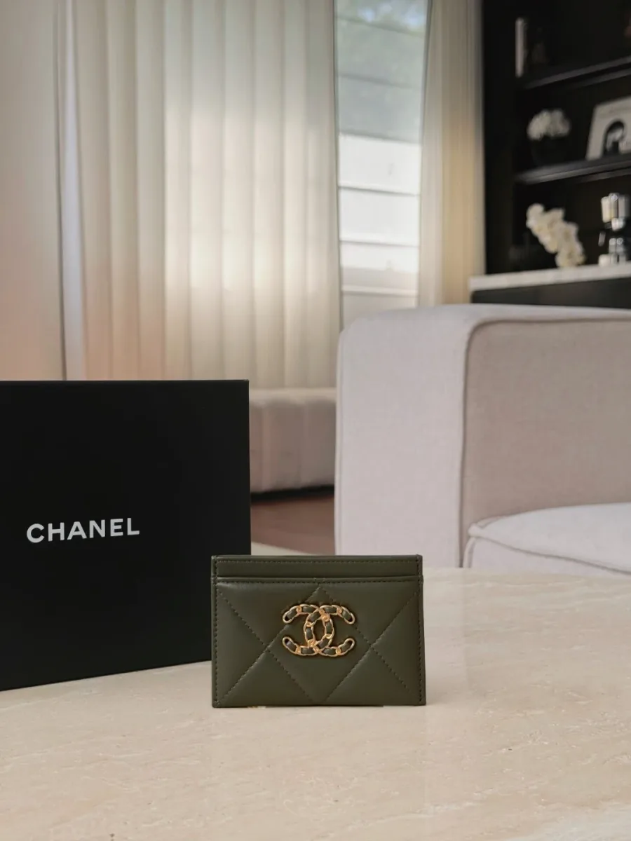 Зелёный картхолдер Chanel 19 с золотистым логотипом CC на фоне коробки