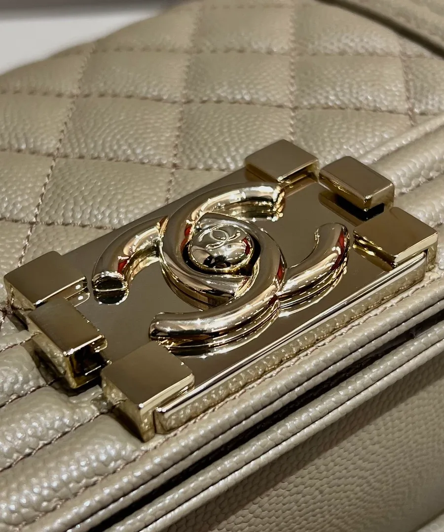 Крупный план золотистого замка с логотипом CC на бежевой сумке Chanel Boy Bag