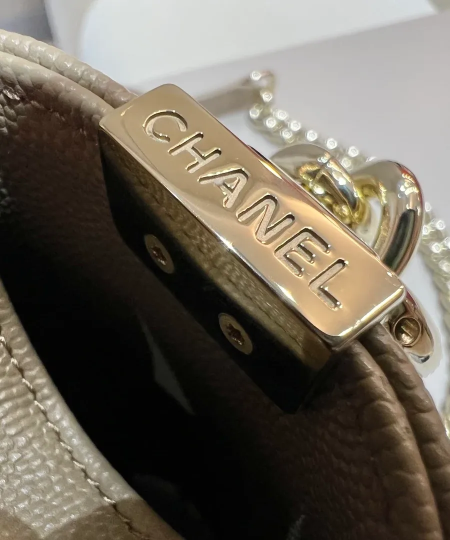 Золотистая металлическая деталь с гравировкой Chanel на боковине сумки