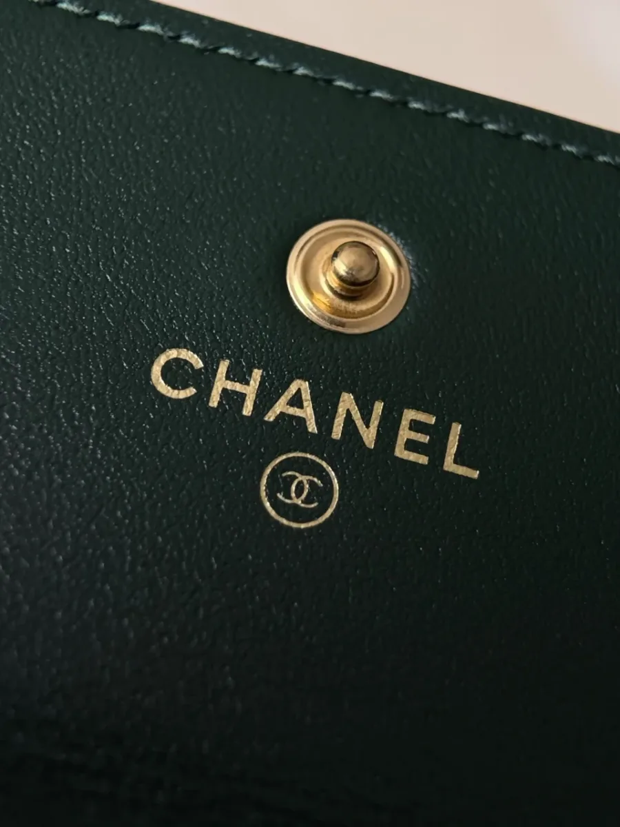 Крупный план золотистого тиснения Chanel и кнопки внутри кошелька