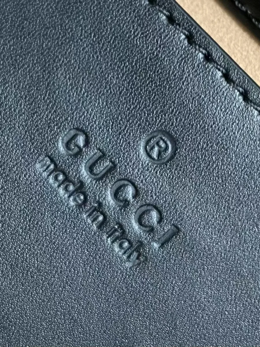 Тиснение логотипа Gucci made in italy на чёрной кожаной бирке внутри сумки