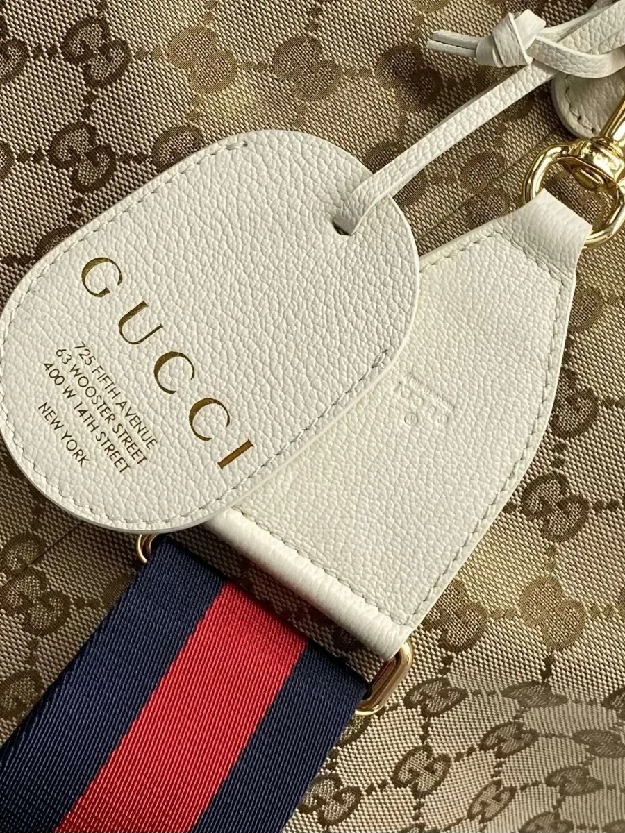 Крупный план белого кожаного ярлыка Gucci и полосатого ремня Web