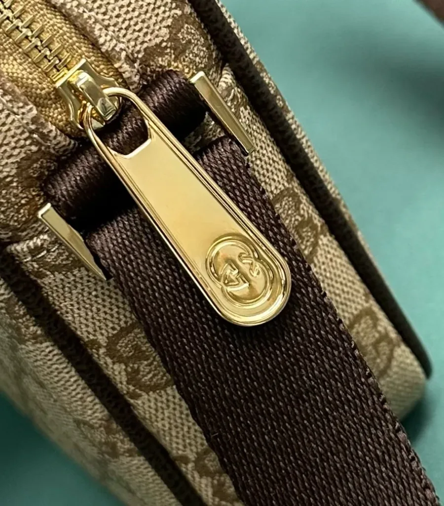 Золотистый металлический пуллер молнии с гравировкой логотипа Gucci