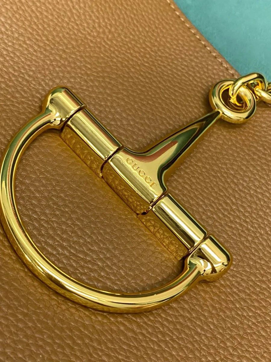 Крупный план золотистой металлической детали Horsebit с гравировкой Gucci
