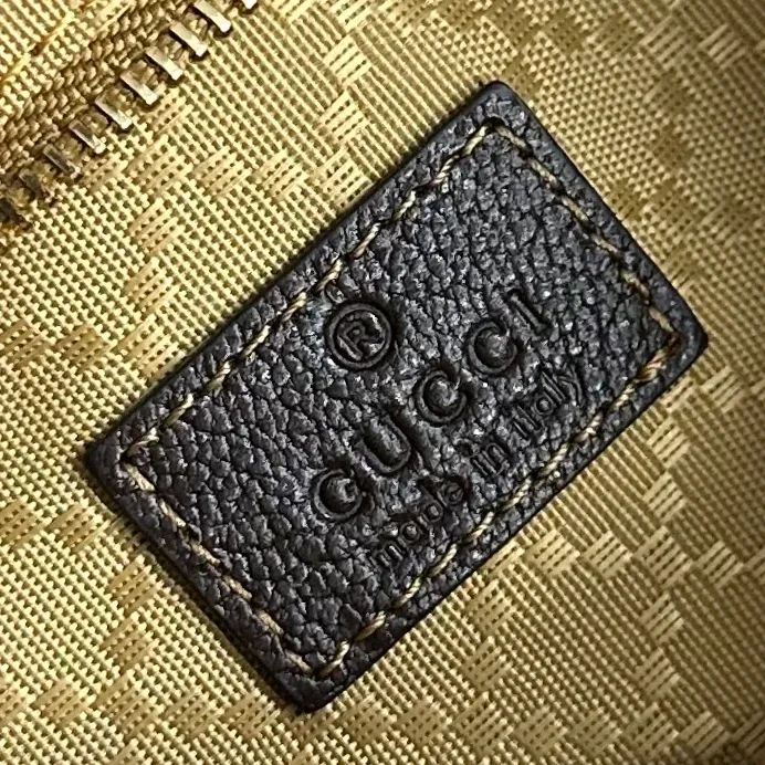 Кожаная бирка с тиснением логотипа Gucci внутри сумки возле застёжки-молнии
