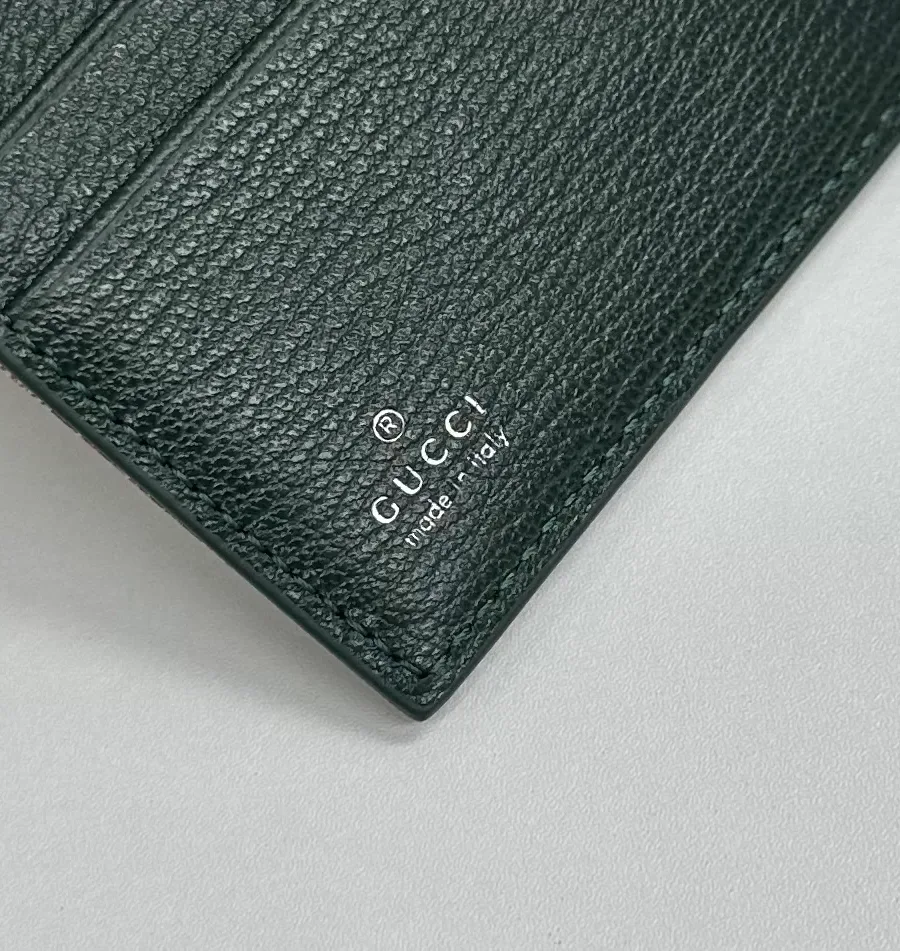Серебристое тиснение логотипа Gucci Made in Italy на зеленом кожаном кармане