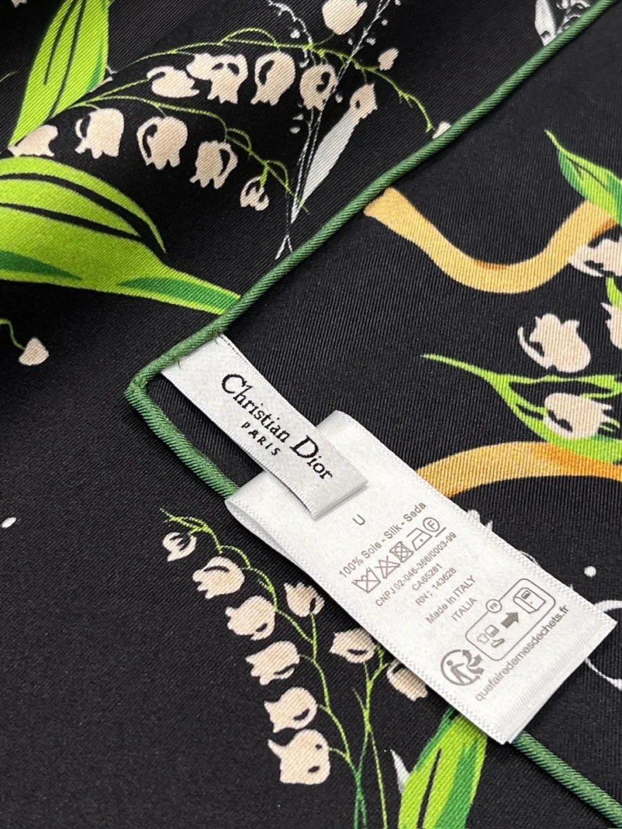Угол платка с ярлыком Christian Dior Paris и контрастной зелёной окантовкой ручной работы.