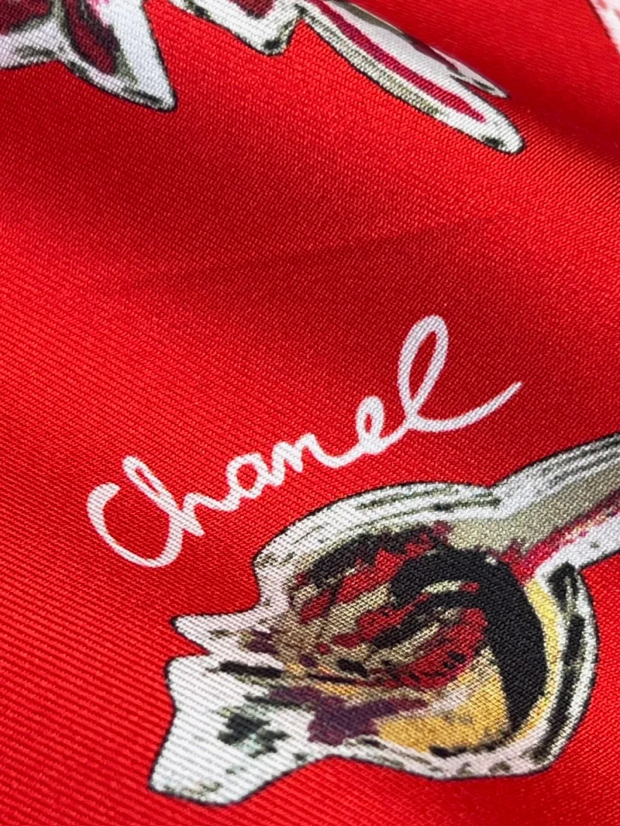 Крупный план шёлковой ткани с напечатанным цветком и логотипом Chanel