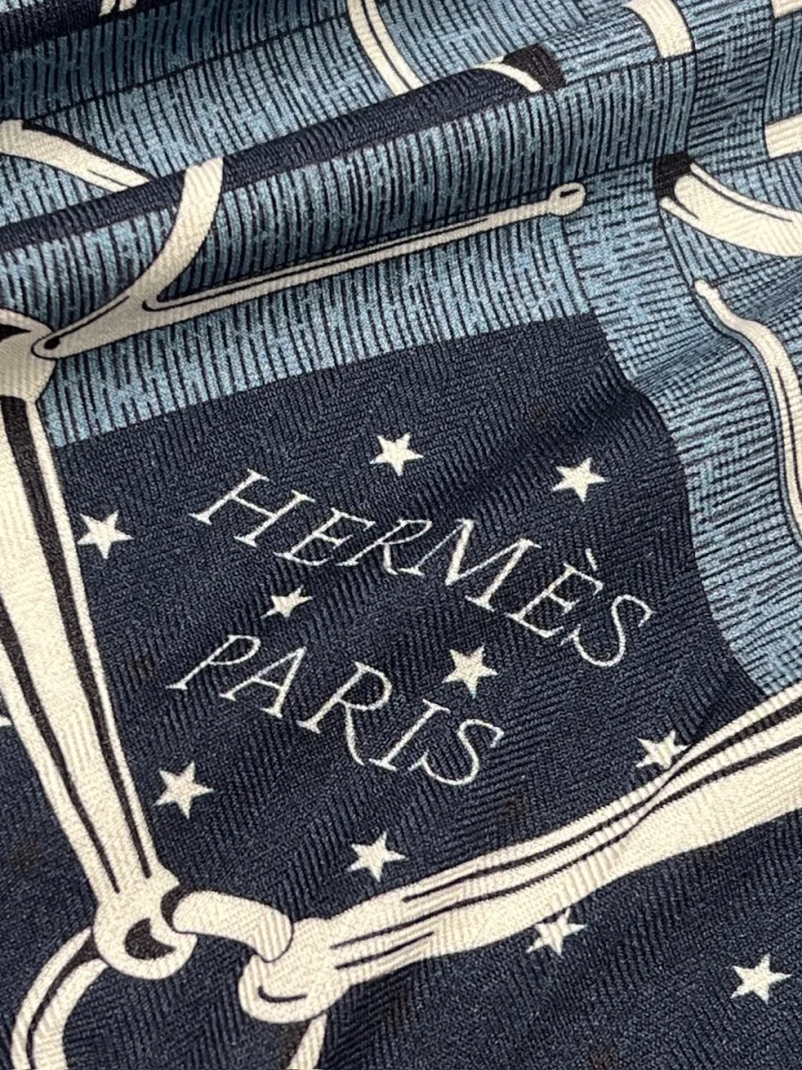 Фрагмент узора синей шали с надписью Hermes Paris и звёздами