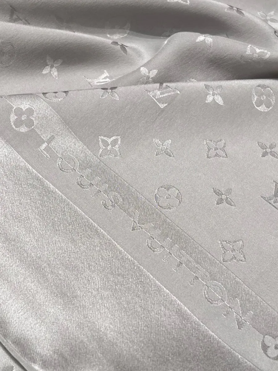Кант шелкового платка с жаккардовой надписью Louis Vuitton крупным планом