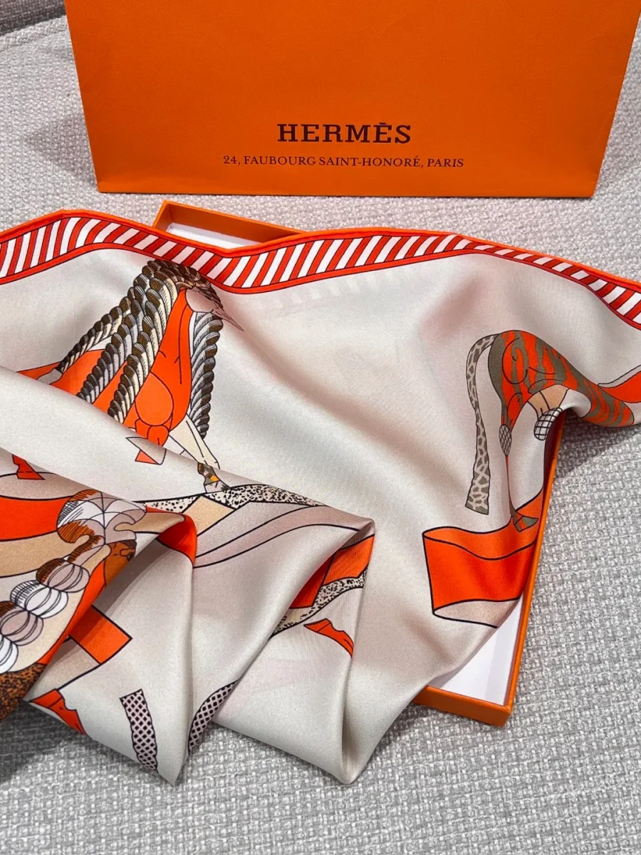 Шёлковый платок Hermes с оранжевым кантом, сложенный возле коробки