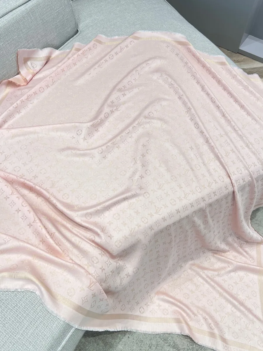 Розовая жаккардовая шаль с узором Monogram, разложенная на светлом диване
