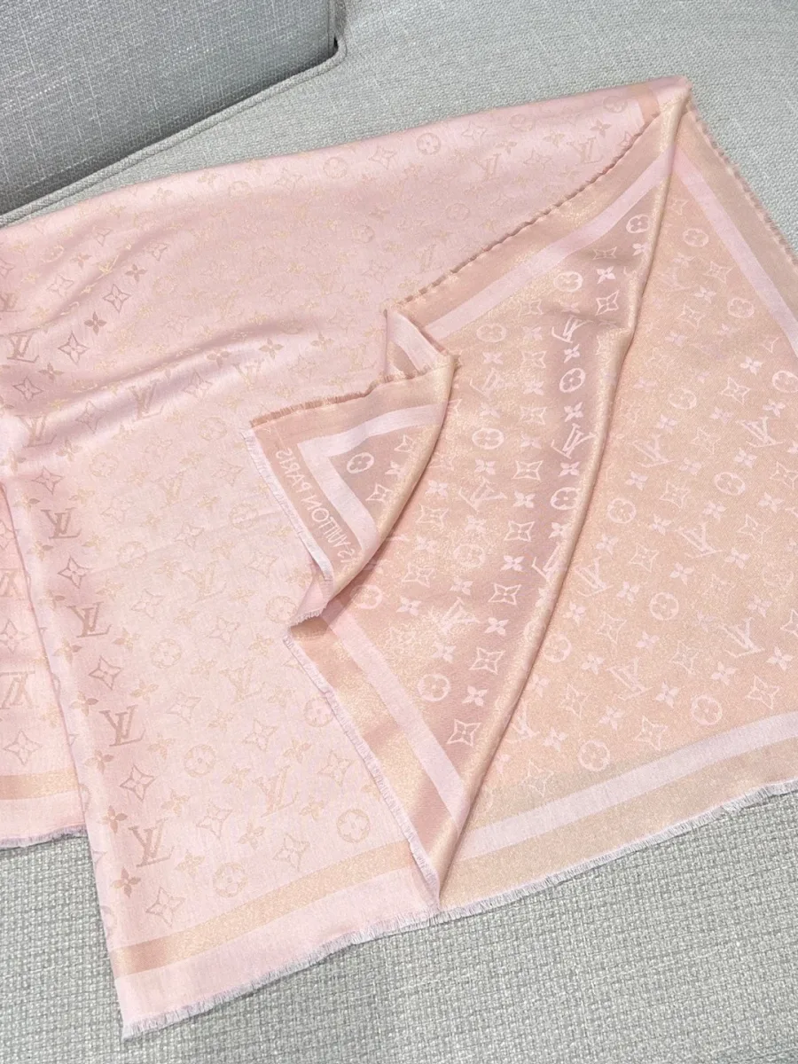 Розовая шаль с узором Monogram и бахромой, сложенная на диване