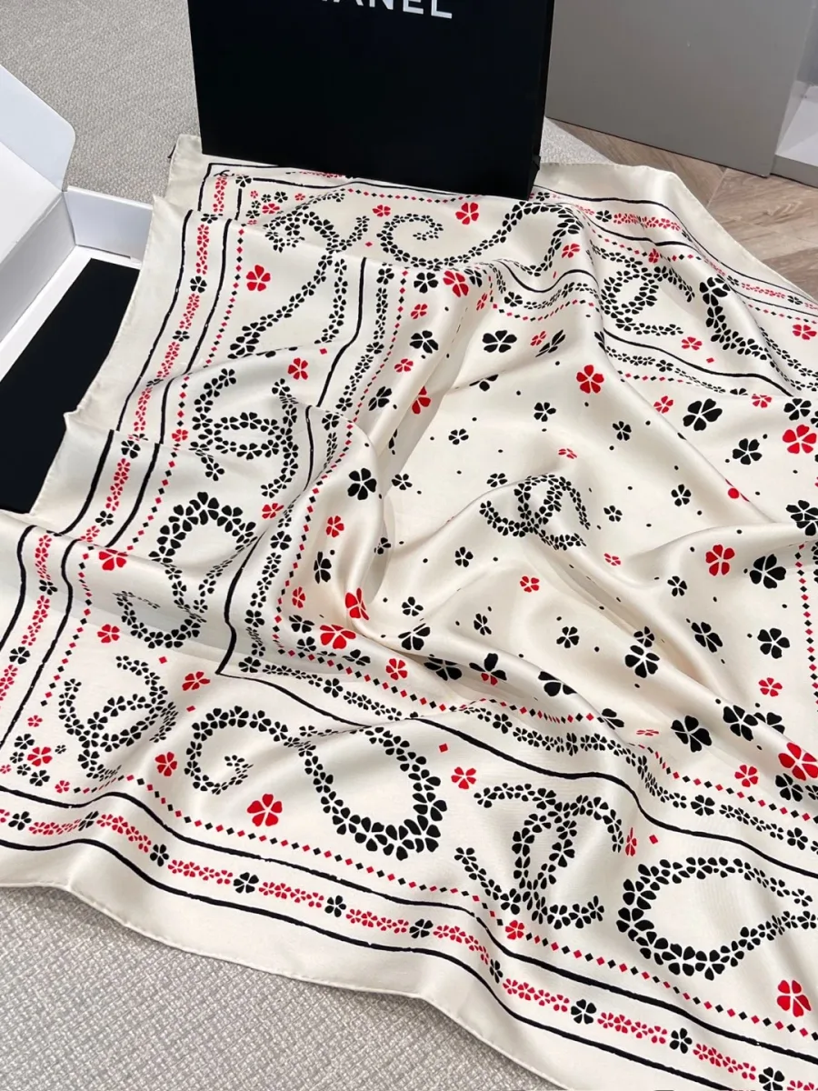 Шёлковый платок Chanel с узором пейсли и монограммами CC, разложенный на столе