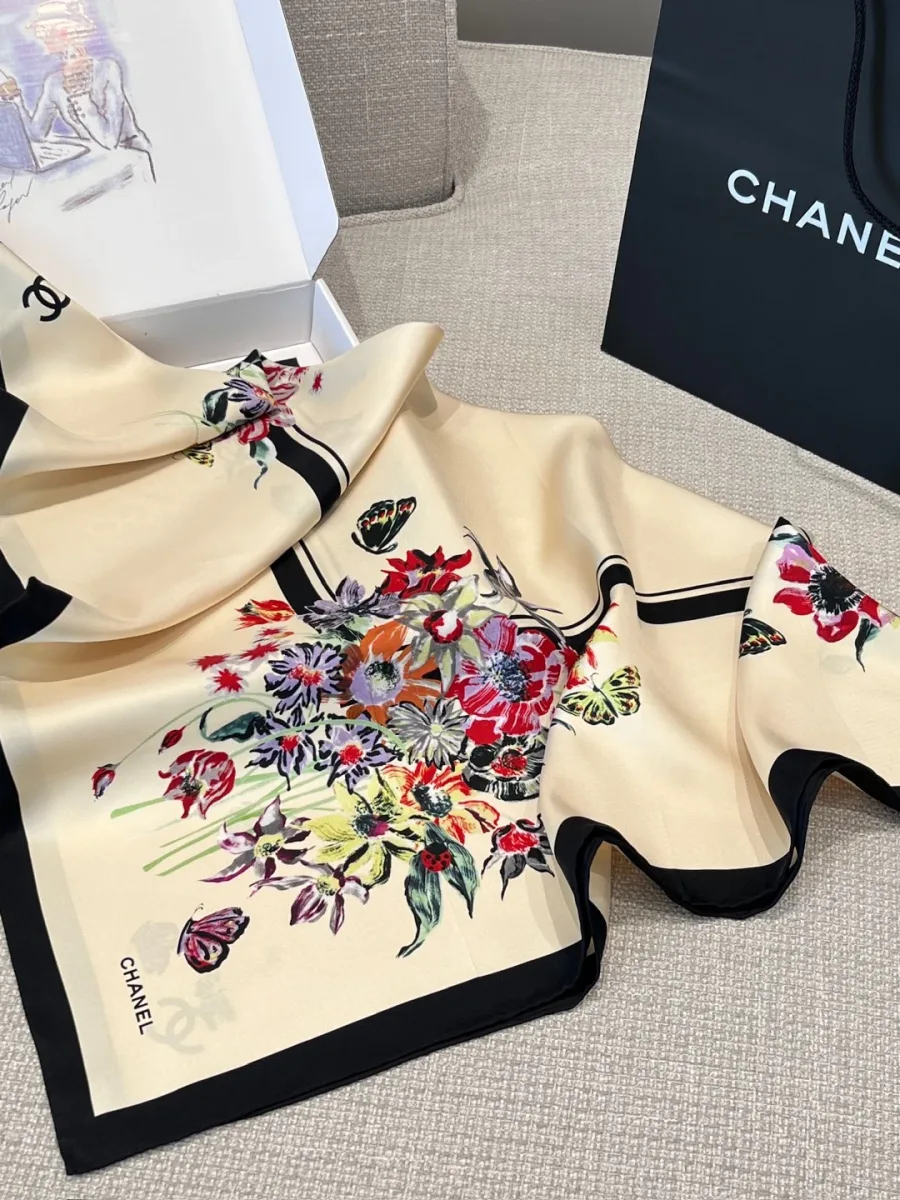 Шёлковый платок Chanel с ярким цветочным узором, сложенный рядом с фирменной коробкой