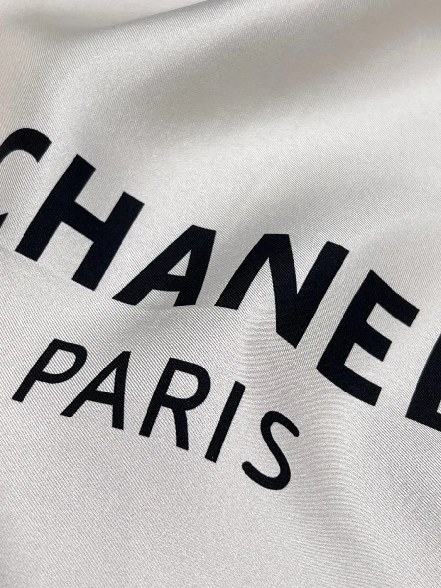 Крупный план гладкой шёлковой ткани платка с принтом Chanel Paris