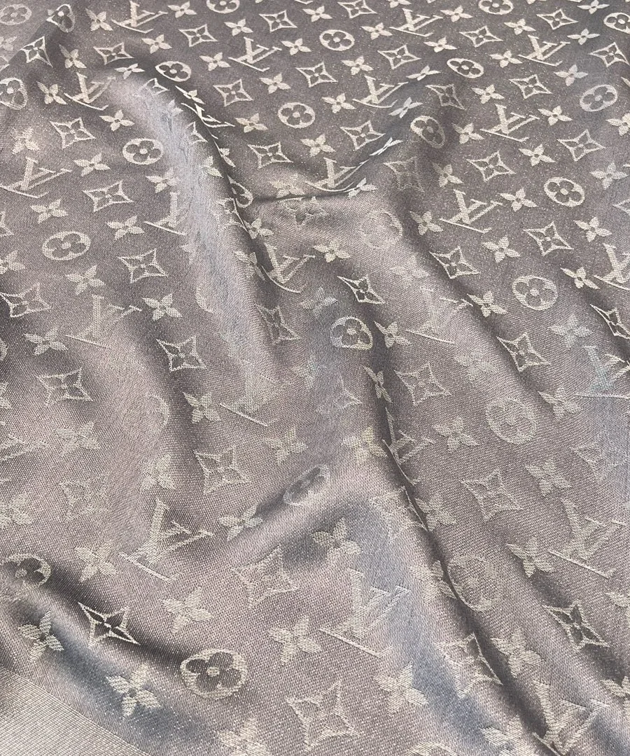 Крупный план фактуры ткани с мерцающей нитью и узором Monogram