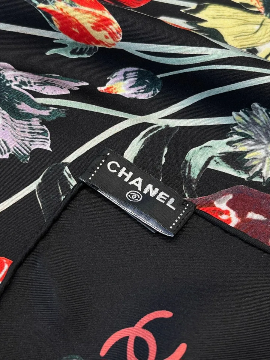 Крупный план края платка с ручной подгибкой и фирменной биркой Chanel