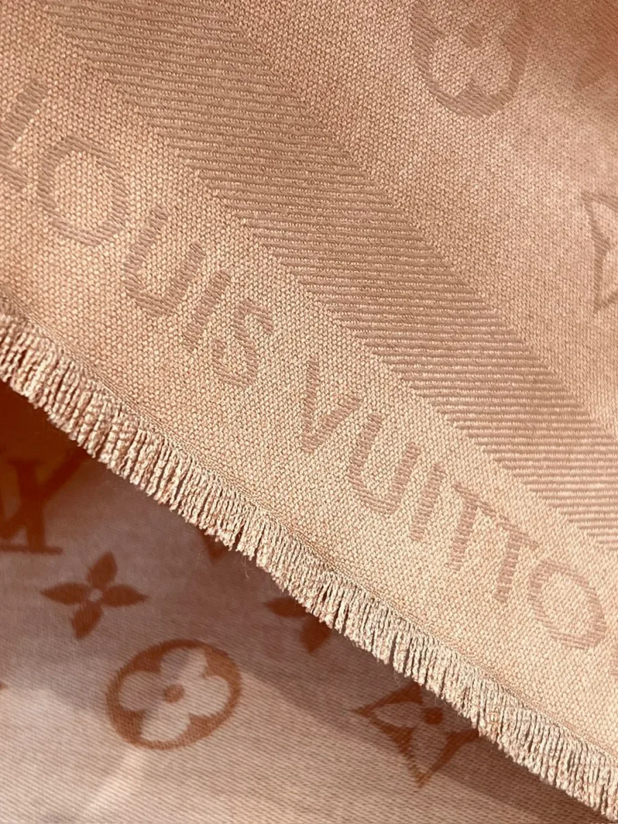 Крупный план жаккардового узора Monogram, надписи бренда и бахромы