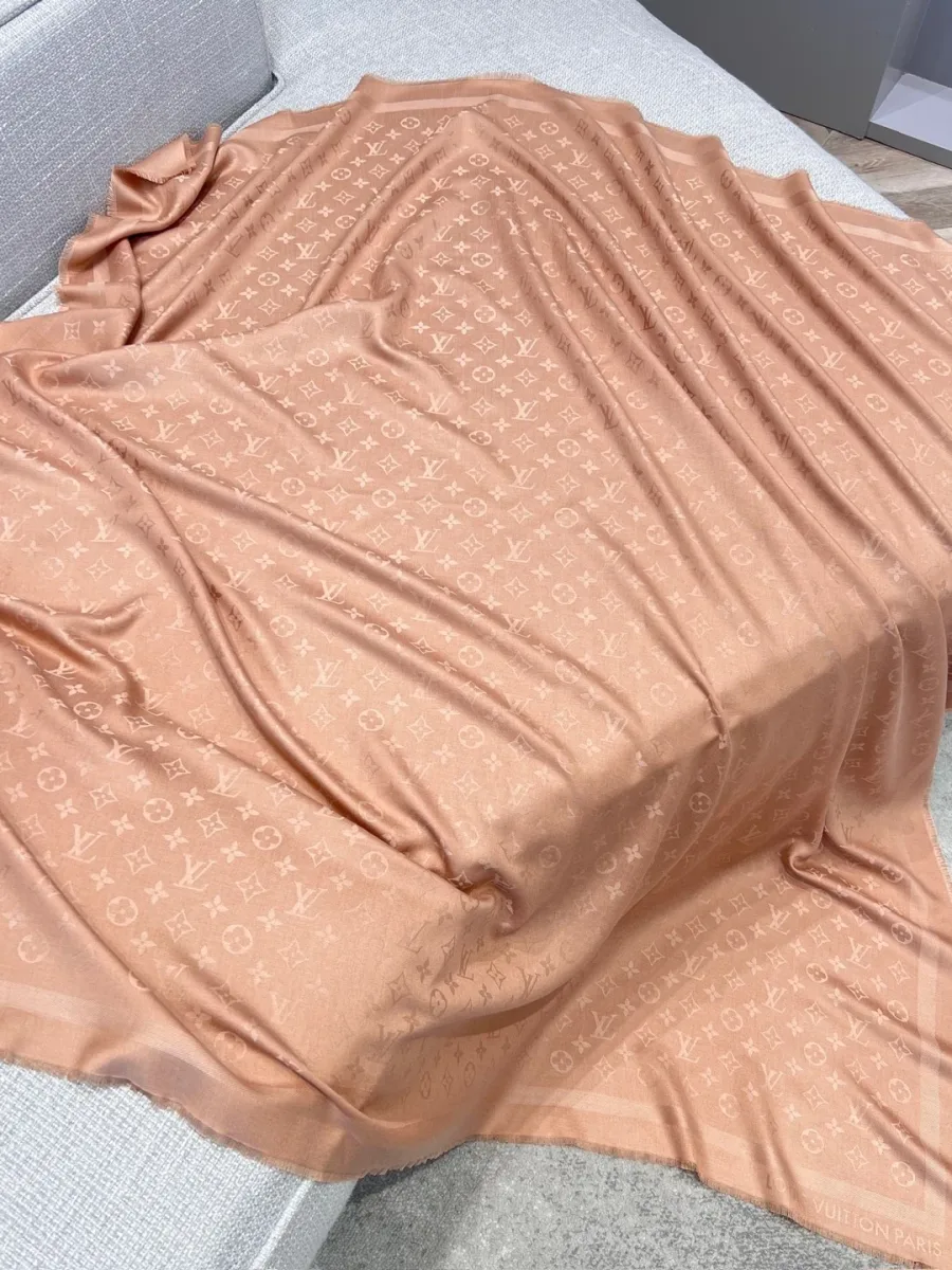 Бежевая шаль с узором Monogram, полностью разложенная на диване