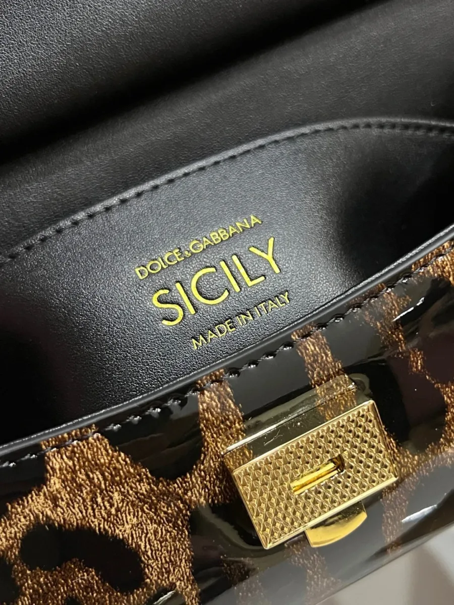 Золотистая застежка и тиснение Sicily под клапаном сумки крупным планом
