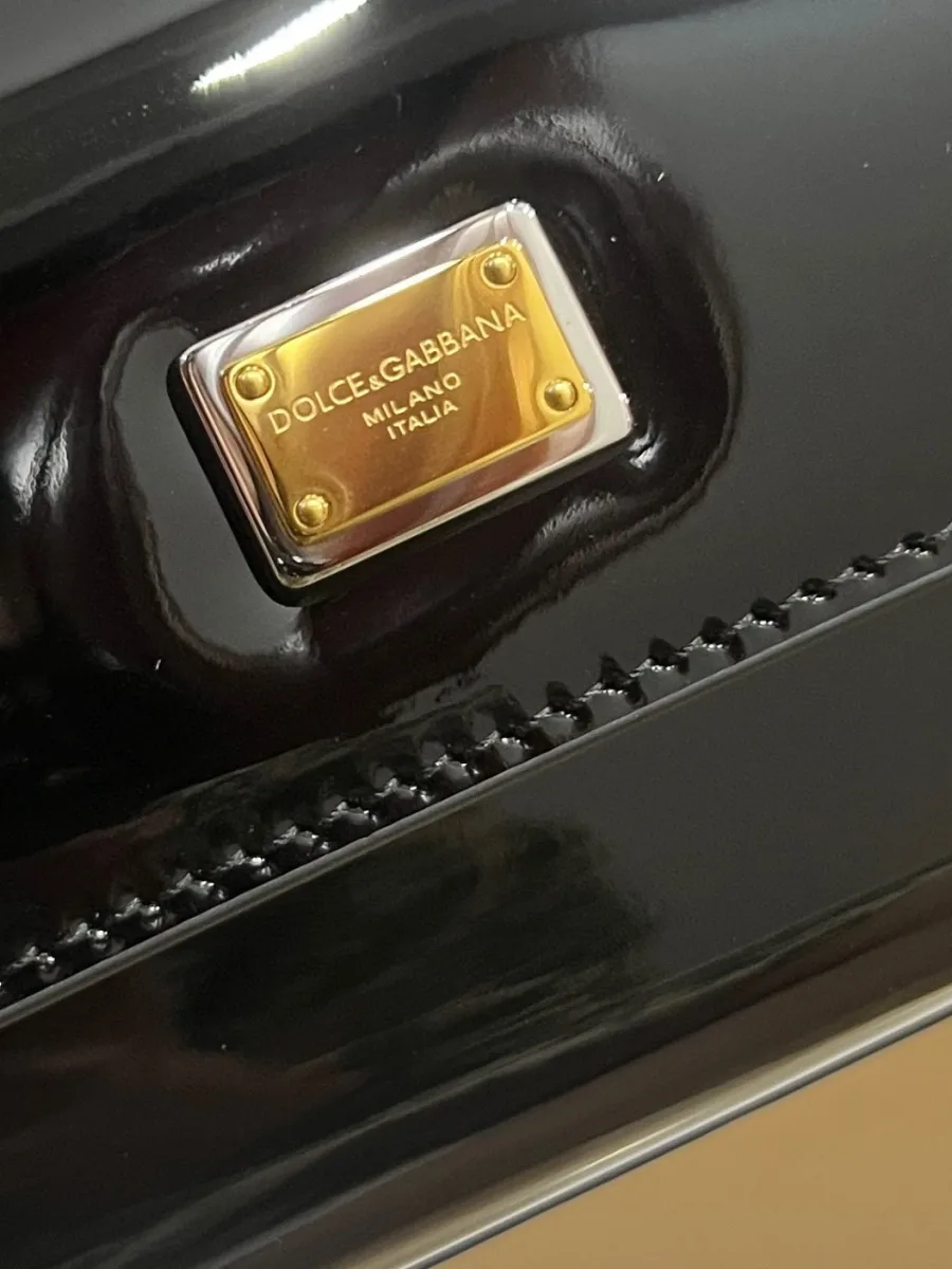 Золотистая металлическая пластина с гравировкой логотипа на клапане сумки крупным планом