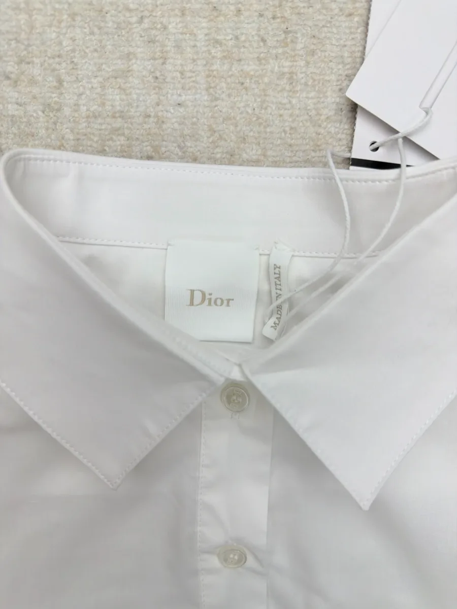 Внутренняя тканевая бирка с логотипом Dior у воротника белой рубашки