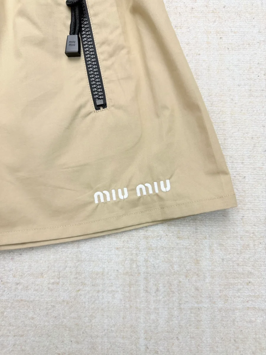 Нижний край юбки с белой вышивкой логотипа бренда Miu Miu
