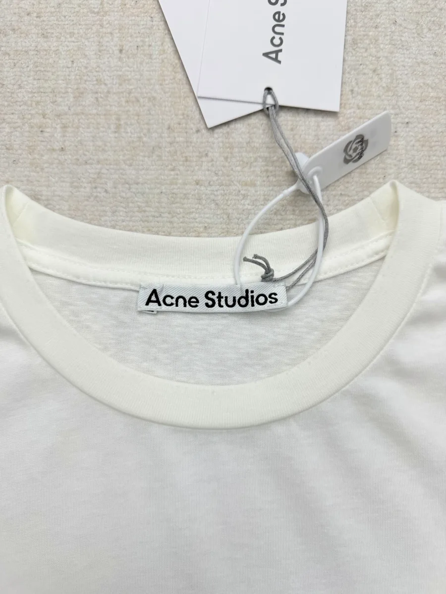 Круглый вырез горловины белого лонгслива с фирменной биркой Acne Studios