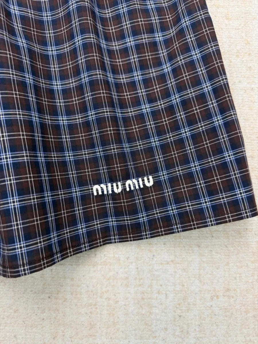 Нижний край юбки с вышитым белым логотипом Miu Miu