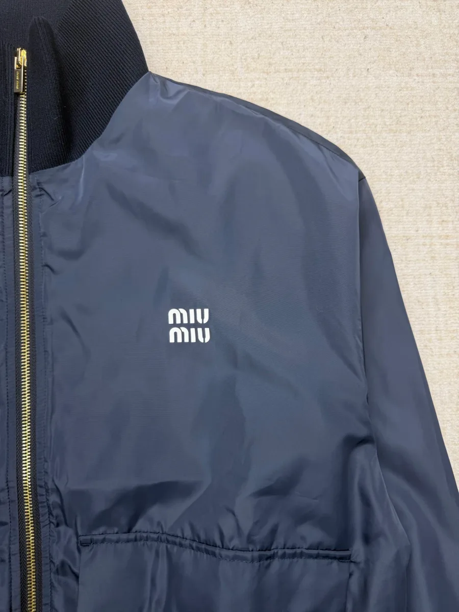 Вышитый контрастный логотип Miu Miu на груди тёмно-синей ветровки