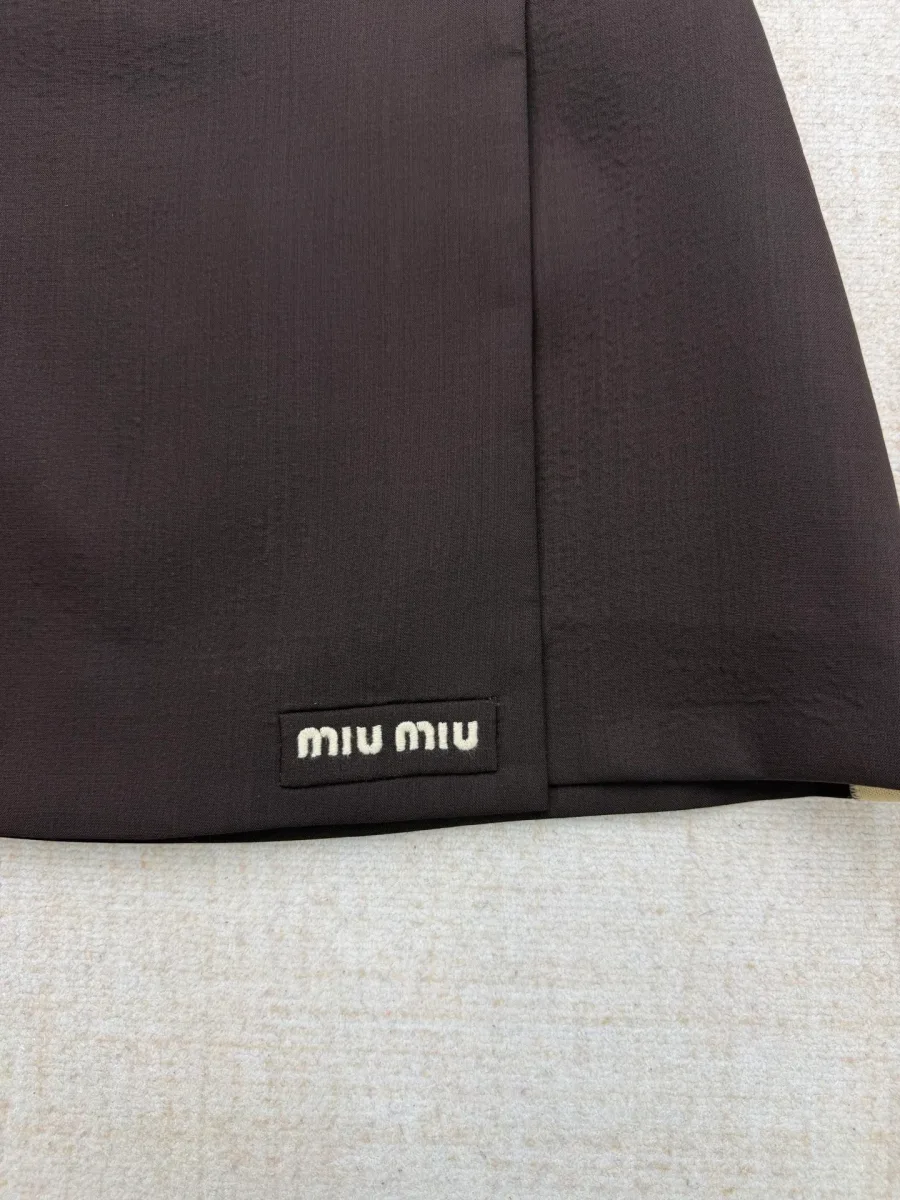 Вышитый контрастный логотип Miu Miu на нижнем крае юбки крупным планом