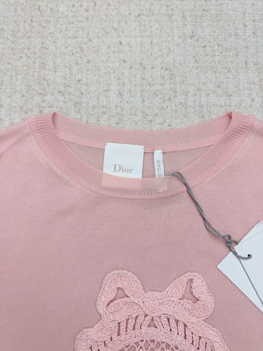 Круглый вырез горловины и бирка Dior на розовой футболке крупным планом