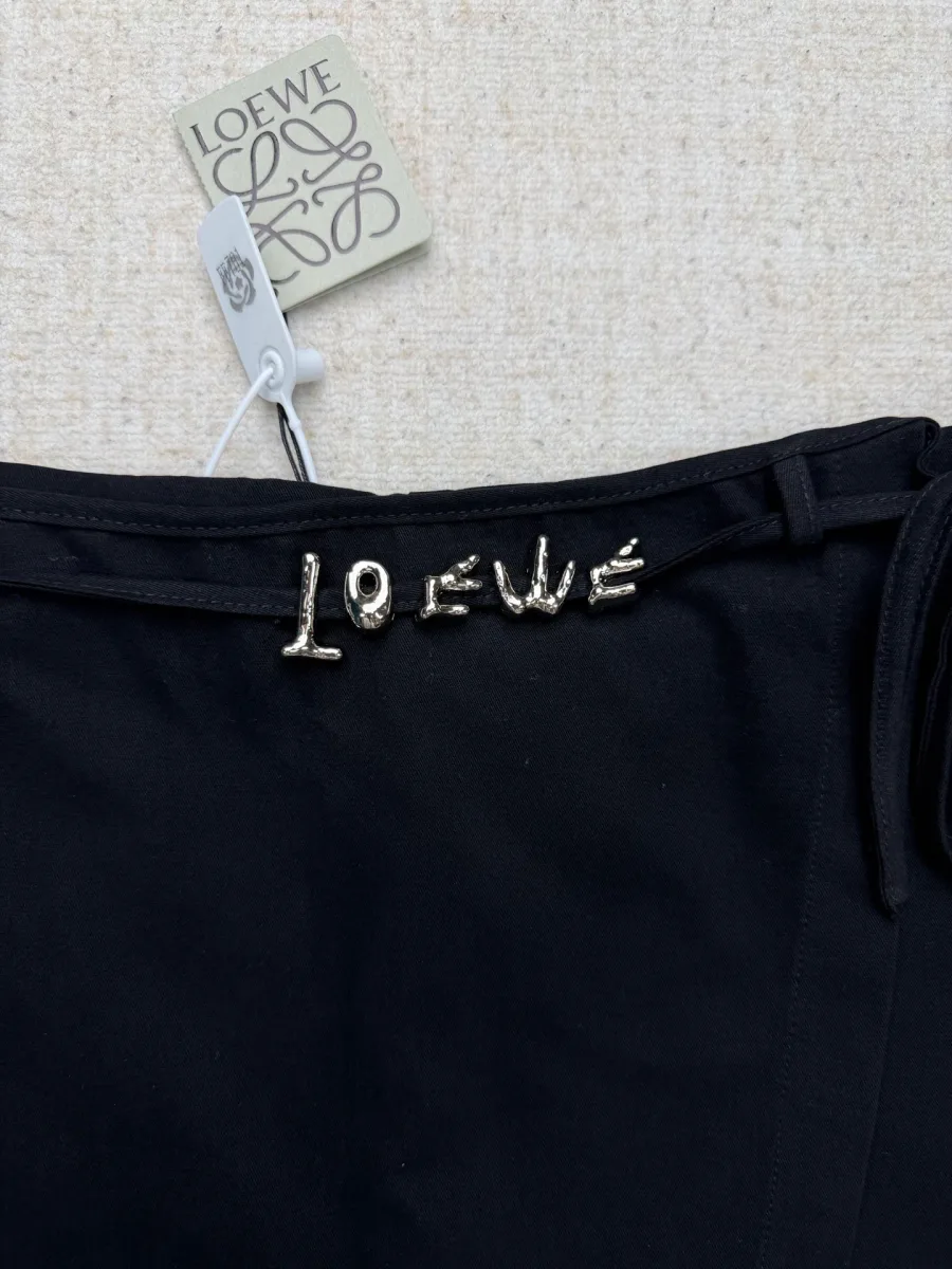 Металлический объёмный логотип Loewe на поясе шорт, крупный план