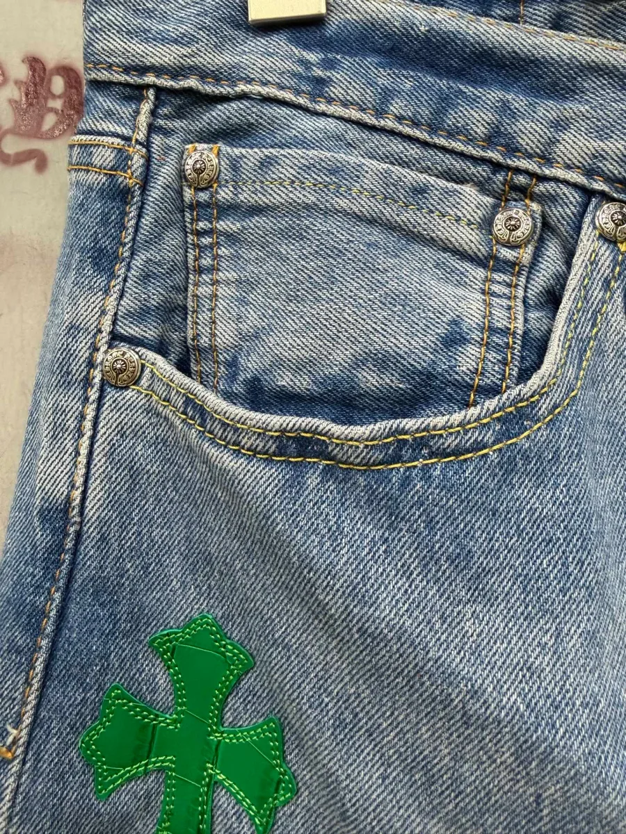 Деталь переднего кармана джинсов Chrome Hearts x Levi's с зеленой нашивкой-крестом